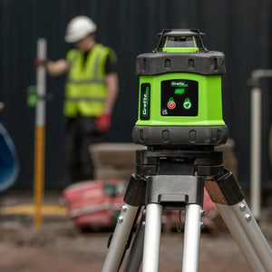 Grettz G60 rotary laser level set up on tripod on a UK construction site with tradesman in high-vis in the background