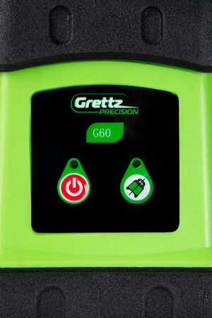 Close-up of the Grettz G60 rotary laser level control panel showing Grettz Precision branding, power button and laser mode button on the green chassis