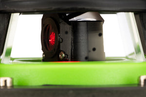 Macro view of the Grettz G60 rotary laser unit emitting its red beam through the protective glass shroud, rotating prism head visible above